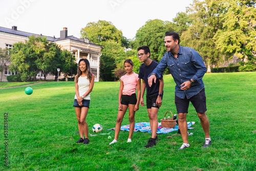 Multiracial family enjoying boules on grass in lawn photo