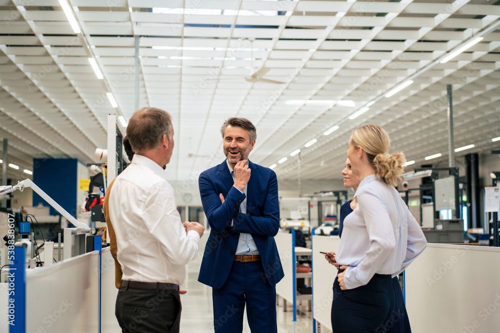 Happy mature businessman discussing with colleagues at industry Happy mature businessman discussing with colleagues at industry