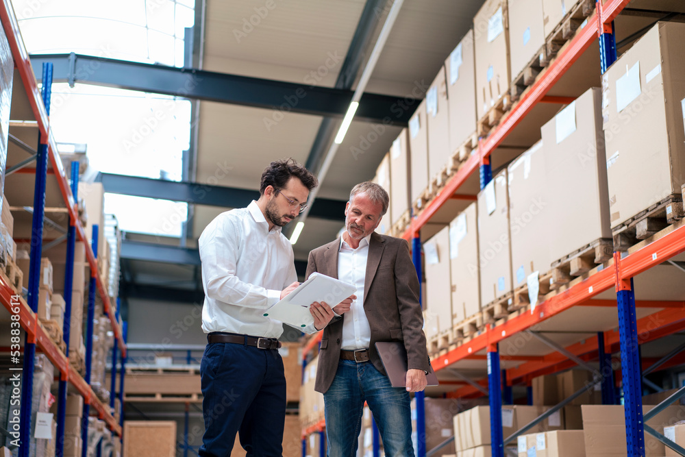Businessman with colleague taking inventory at warehouse Businessman with colleague taking inventory at warehouse