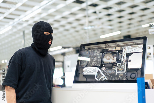 Robber standing by computer at warehouse photo