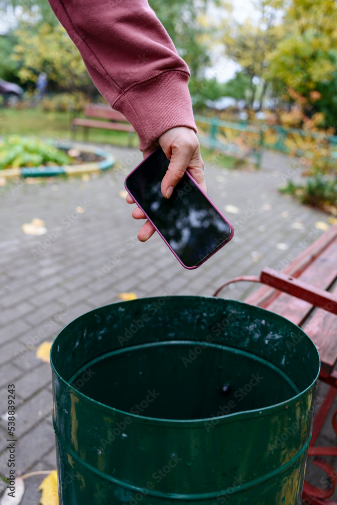 Hand of man throwing mobile phone in garbage bin Photos | Adobe Stock