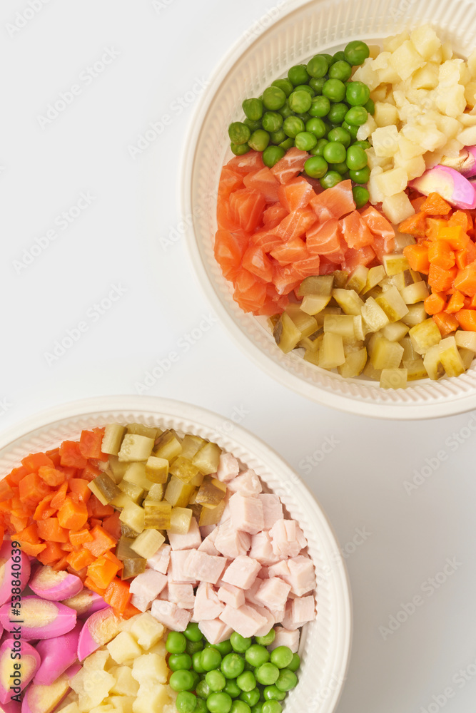 Bowls with Olivier salad ingredients against white background Bowls with Olivier salad ingredients against white background