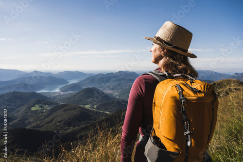 Woman standing with backpack in front of mountains at vacation