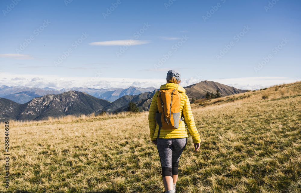 Mature woman walking with backpack on sunny day Mature woman walking with backpack on sunny day