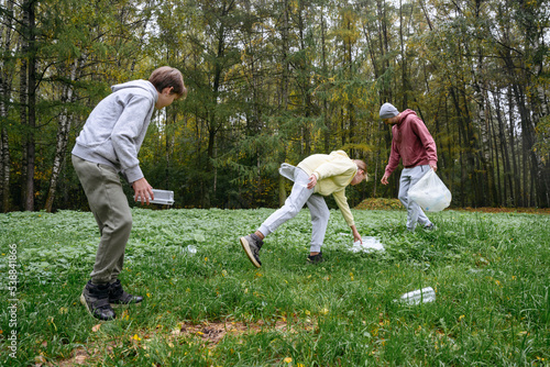 Man with children collecting garbage from grass