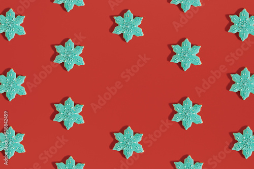 Creative Christmas pattern made of snowflake shaped.cookies on bold red background. New Year cozy decoration. Holiday flat lay aesthetic. Minimal visual with copy space.