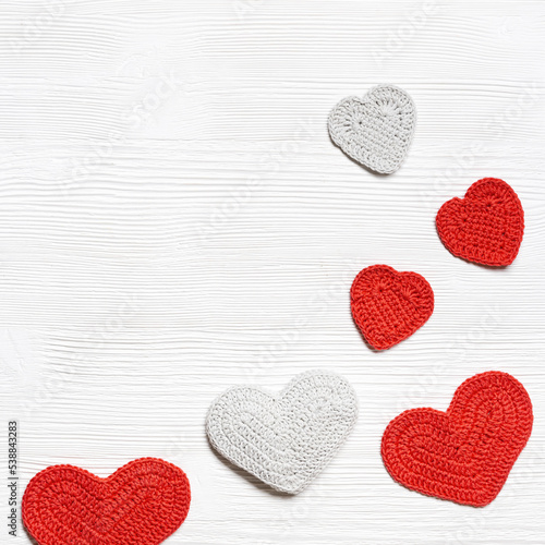 Valentines day background, knit hearts valentine, handmade red crochet heart on white wood table, handmade gift for romance holiday, symbol of love. Festive card with copy space. Top view