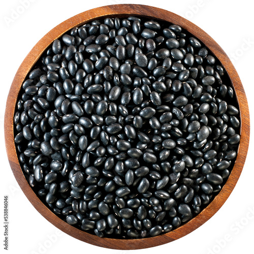 Black beans in a round wooden tray, flat lay.