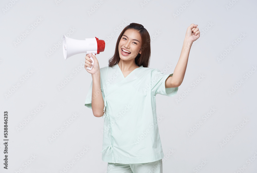 Asian patient woman wearing patient gown shouting loud holding a megaphone speaking for compensation coverage or tell insurance agent or hospital for emergency. Asian patient woman wearing patient gown shouting loud holding a megaphone speaking for compensation coverage or tell insurance agent or hospital for emergency.