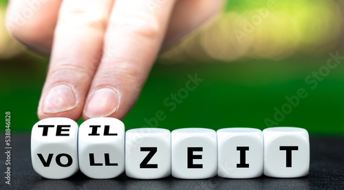 Hand turns dice and changes the German expression 'vollzeit' (full time) to 'teilzeit' (part time). photo