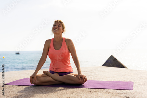 Beautiful young woman practising yoga outside. Fit woman doing stretching exercises at the beach.