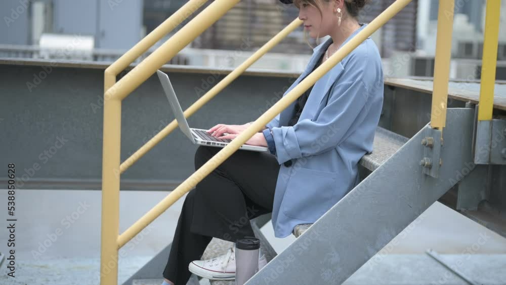 外の階段にすわって仕事をする女性 外の階段にすわって仕事をする女性