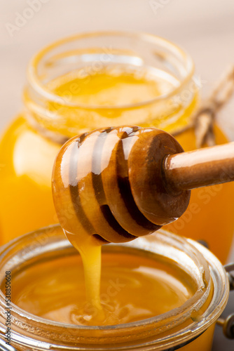 Honey on wooden honey-dipper closeup food background