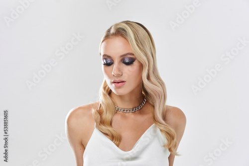 Portrait of blonde woman with smokey eyes make-up and wavy hairstyle. Black polish nails