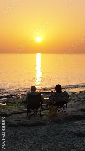 Vertiical video People sit on the beach and watch the sunset photo