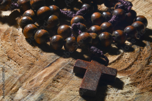 wooden cross with rosary crown on tree trunk background