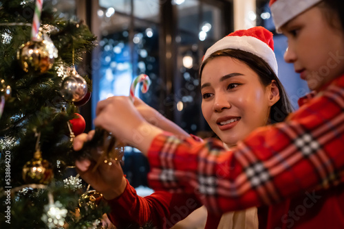 Asian beautiful mother and daughter decorating Christmas tree at home. 