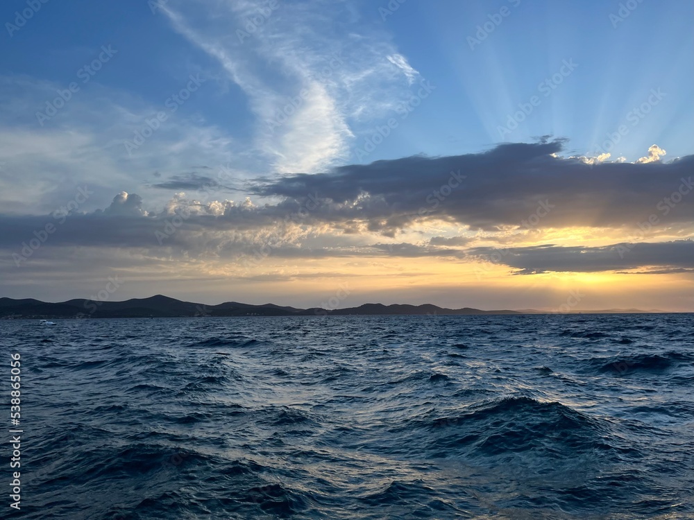 Obraz premium Sunset at the sea, sea horizon, sun rays through the clouds