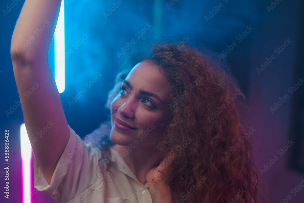 Portrait of a happy young woman dancing over neon light background at disco party Portrait of a happy young woman dancing over neon light background at disco party