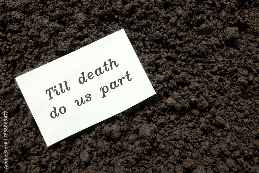 Till death do us part wedding vow concept. Handwritten note on paper on grave soil.