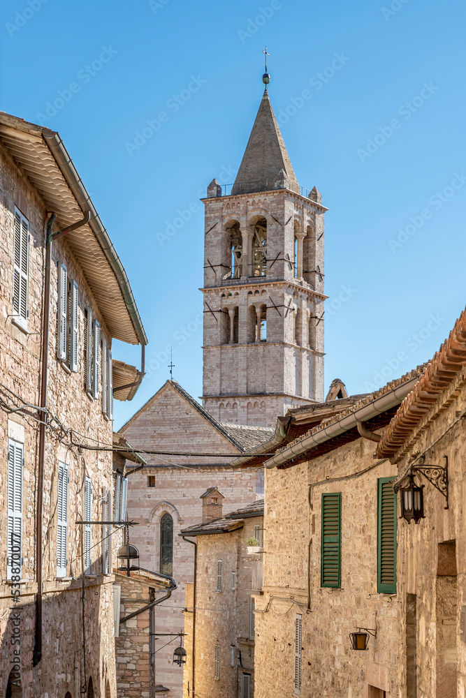 The bell tower of the basilica of Santa Chiara framed by the buildings of the historic center of Assisi, Italy