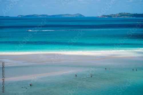 tourists walking on the beach in the whitsundays queensland, australia. travellers on the great barrier reef, over coral and fish. tourism yachts of young people partying on the water