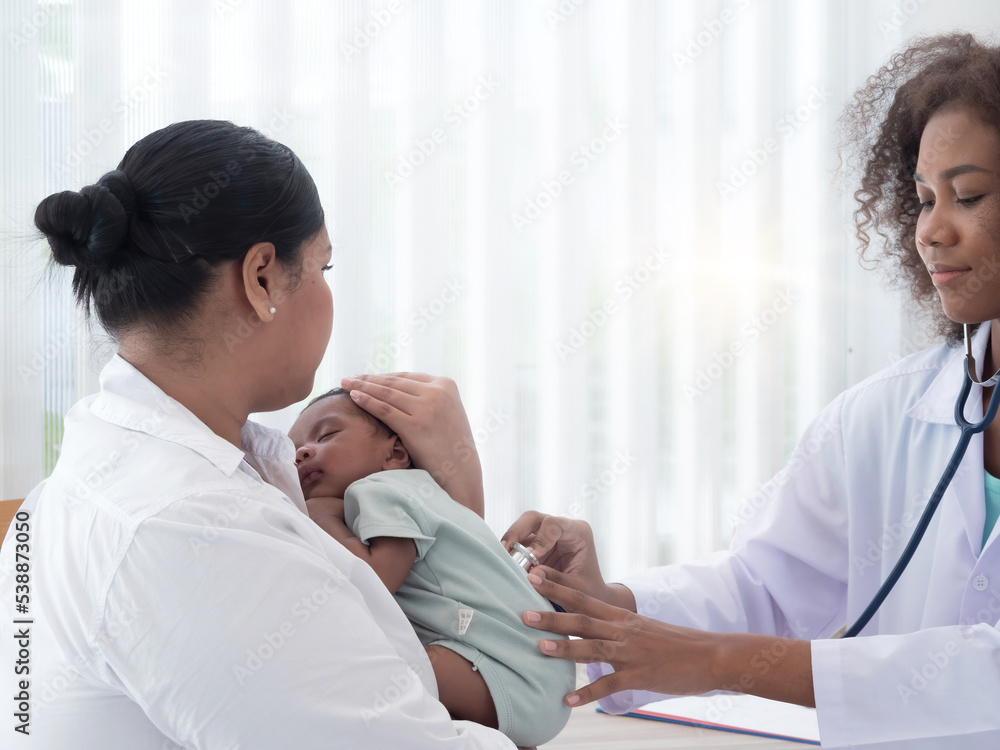 Obraz premium Young pediatrian checking the well being of little baby boy who's sleeping in mother's arms. Health and well being concept.