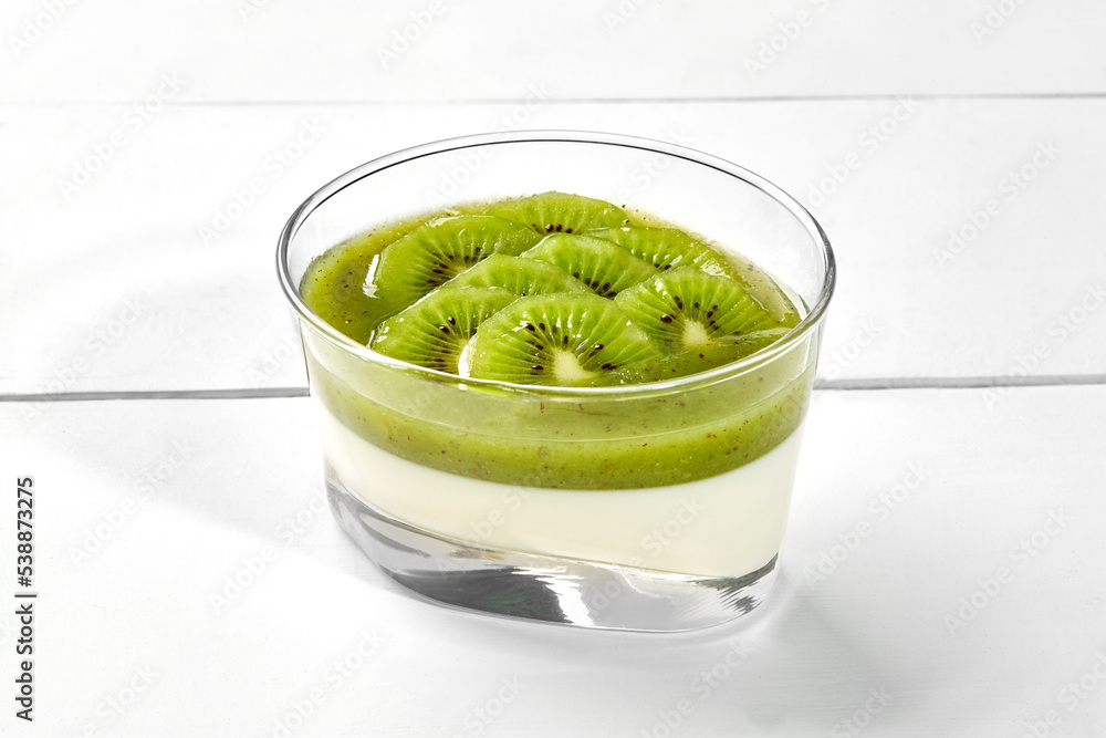 Coconut panna cotta with kiwi and mint coulis in glass on white wooden background Coconut panna cotta with kiwi and mint coulis in glass on white wooden background
