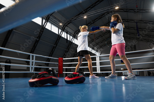 Two athletes, little girl, beginner kickboxer training with female coach at sports gym, indoors. Concept of studying, challenges, sport, hobbies, competition © master1305