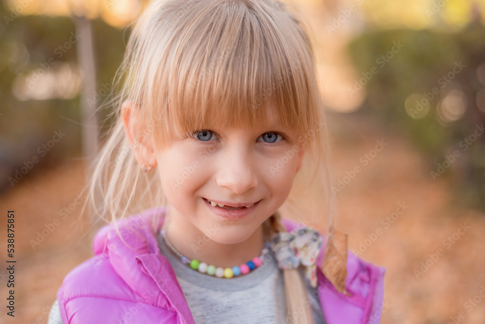 Portrait of a fair-haired girl. The child walks in the autumn park.