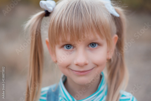 Portrait of a fair-haired girl. Blue-eyed girl with bows on her hair.