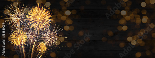 Sylvester, New Year's Eve 2023 Party, New year, Firework celebration background banner panorama long- Golden fireworks and bokeh lights on black rustic wooden wall texture in the night.