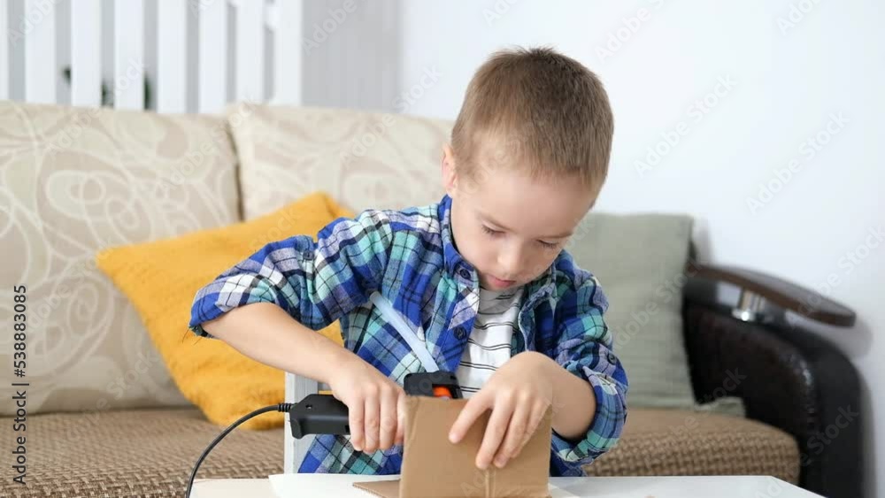Boy use hot melt glue gun making yourself crafts from cardboard. Supporting creativity handcraft, creative leisure for children at home. Boy use hot melt glue gun making yourself crafts from cardboard. Supporting creativity handcraft, creative leisure for children at home.
