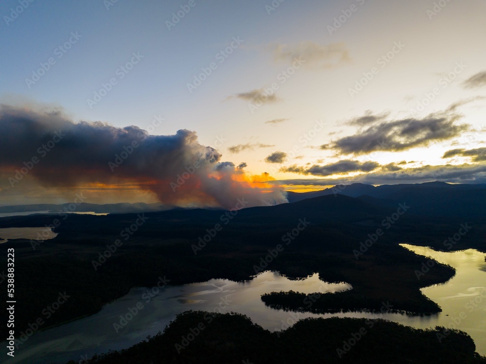 smoke rising over a hill in tasmania australia, from a bushfire in australia in summer.