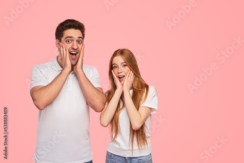 Amazed young couple looking at camera