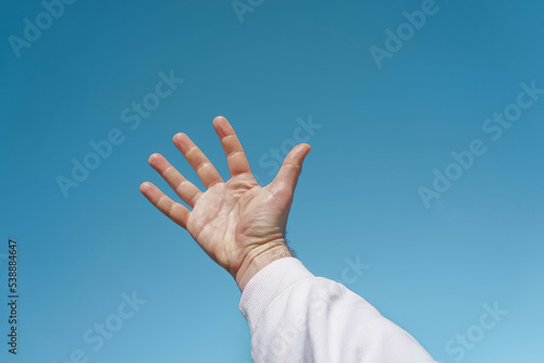 hand up in the air gesturing in the blue sky, blue background