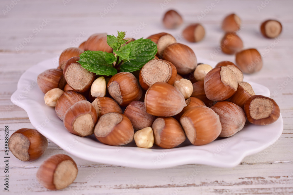 Hazelnuts in a porcelain plate on a white wooden background.Close-up.
Hazelnuts in a porcelain plate on a white wooden background.Close-up.