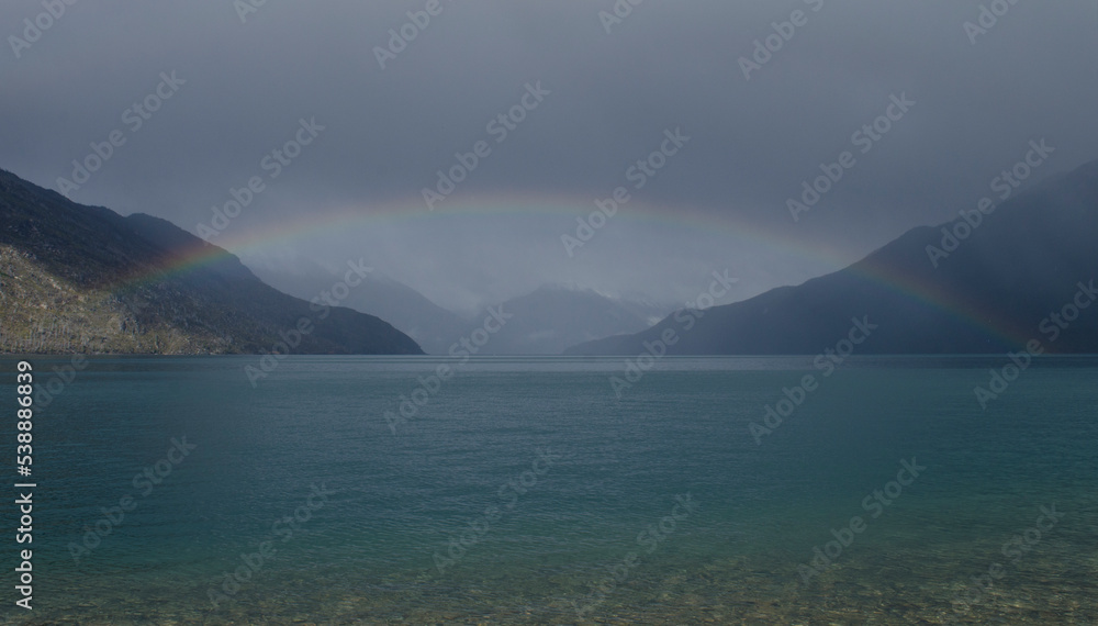 full rainbow on the lake. rainbow of colors in the middle of a lake with mountains. in puelo lake