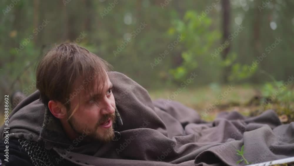 Injured warrior in medieval chain mail and cape falls down on ground in wood during battle closeup slow motion. Hard enemy attack. Role playing Injured warrior in medieval chain mail and cape falls down on ground in wood during battle closeup slow motion. Hard enemy attack. Role playing
