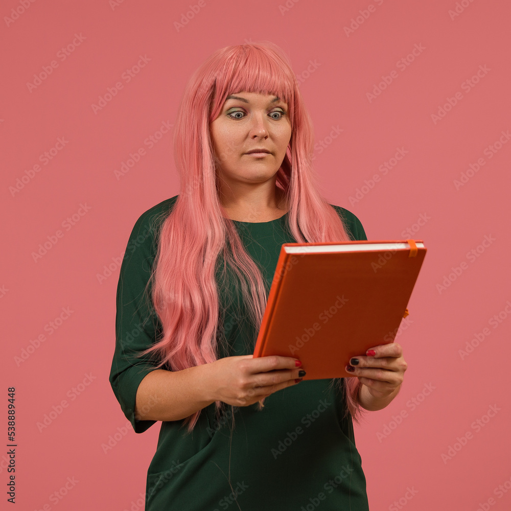 a woman with pink hair looks with surprise at a book in her hands a woman with pink hair looks with surprise at a book in her hands