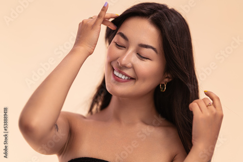Happy Asian woman touching hair