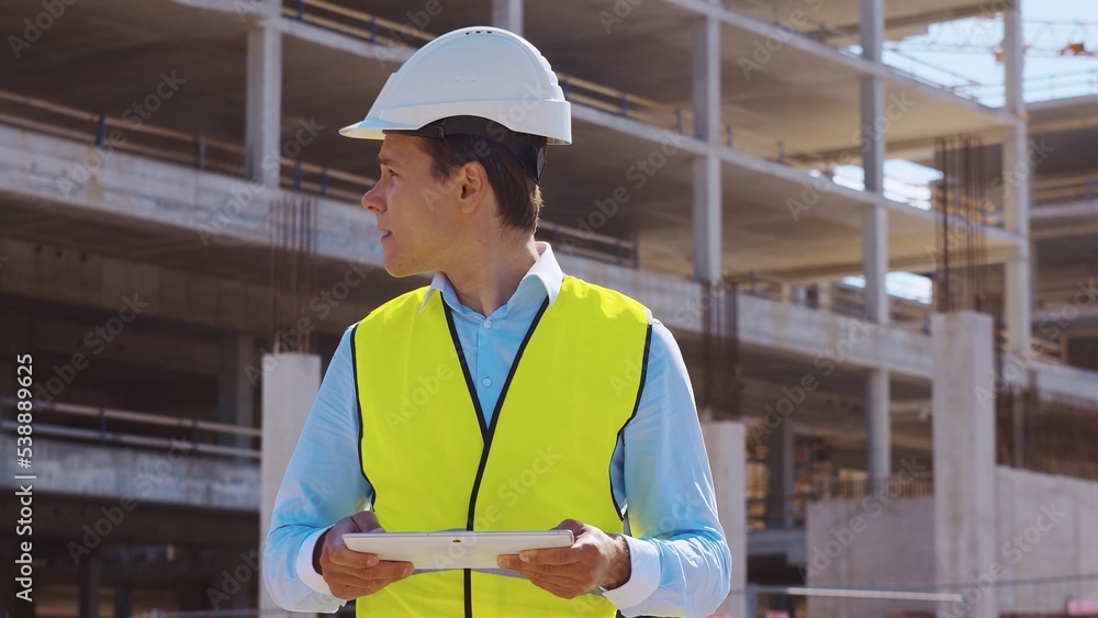 Professional builder standing in front of construction site. Foreman in hardhat helmet and vest. Office building and crane background. Business, real estate and investment. Professional builder standing in front of construction site. Foreman in hardhat helmet and vest. Office building and crane background. Business, real estate and investment.
