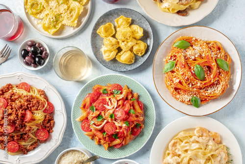 Pasta, many different varieties, overhead flat lay shot. Italian food and drinks, shot from the top. Spaghetti in tomato sauce, chicken pasta, Bolognese, ravioli, olives, and wine