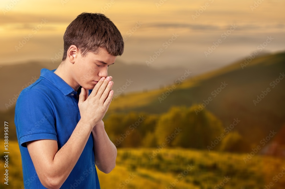 Young person praying on beautiful nature background. Young person praying on beautiful nature background.