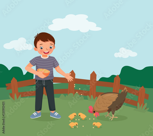 happy little boy feeding chickens on the farm 