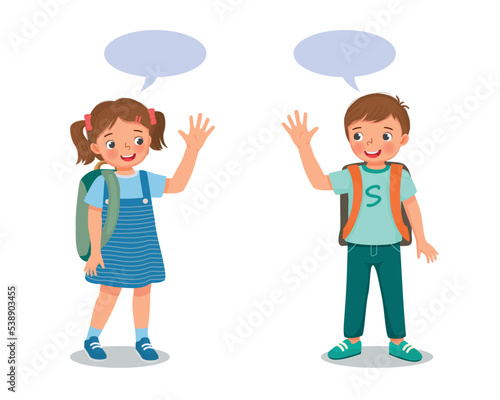 two cute schoolkids with backpack boy and girl say goodbye or hello waving hands to each others