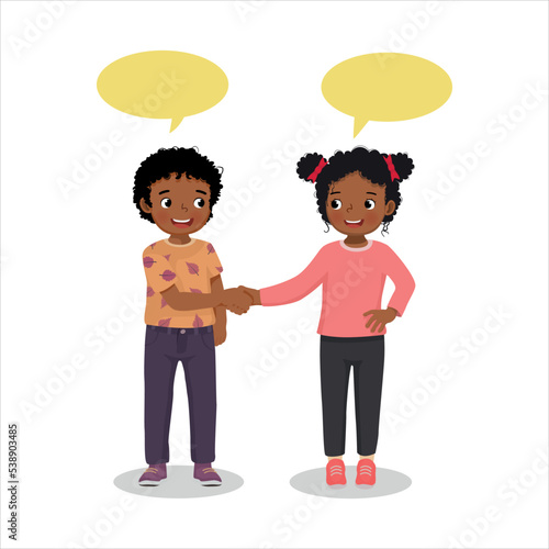 Two cute little African kids boy and girl shaking hands making introduction or congratulating to each others