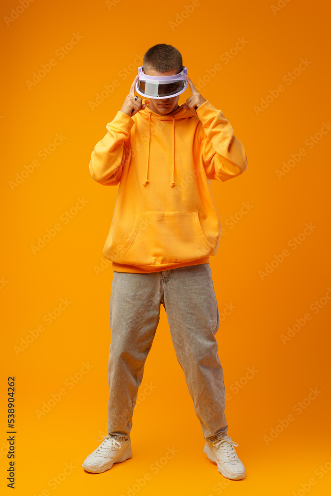 Young urban style man in sweatshirt and visor on yellow studio background Young urban style man in sweatshirt and visor on yellow studio background