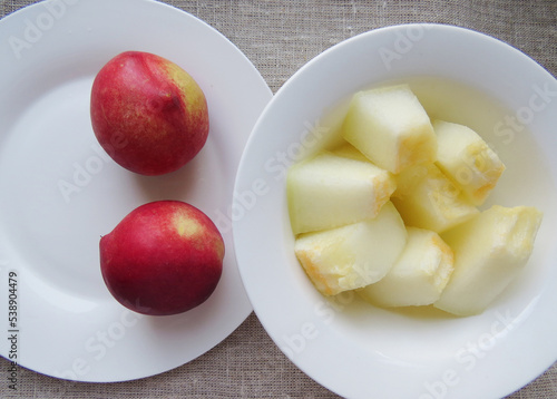 Peach and  Juicy pulp of ripe sliced  melon on a white plate. Top viewOrganic summer natural background Photo photo