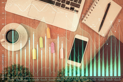 Double exposure of financial chart hologram over desktop with phone. Top view. Mobile trade platform concept. © peshkova